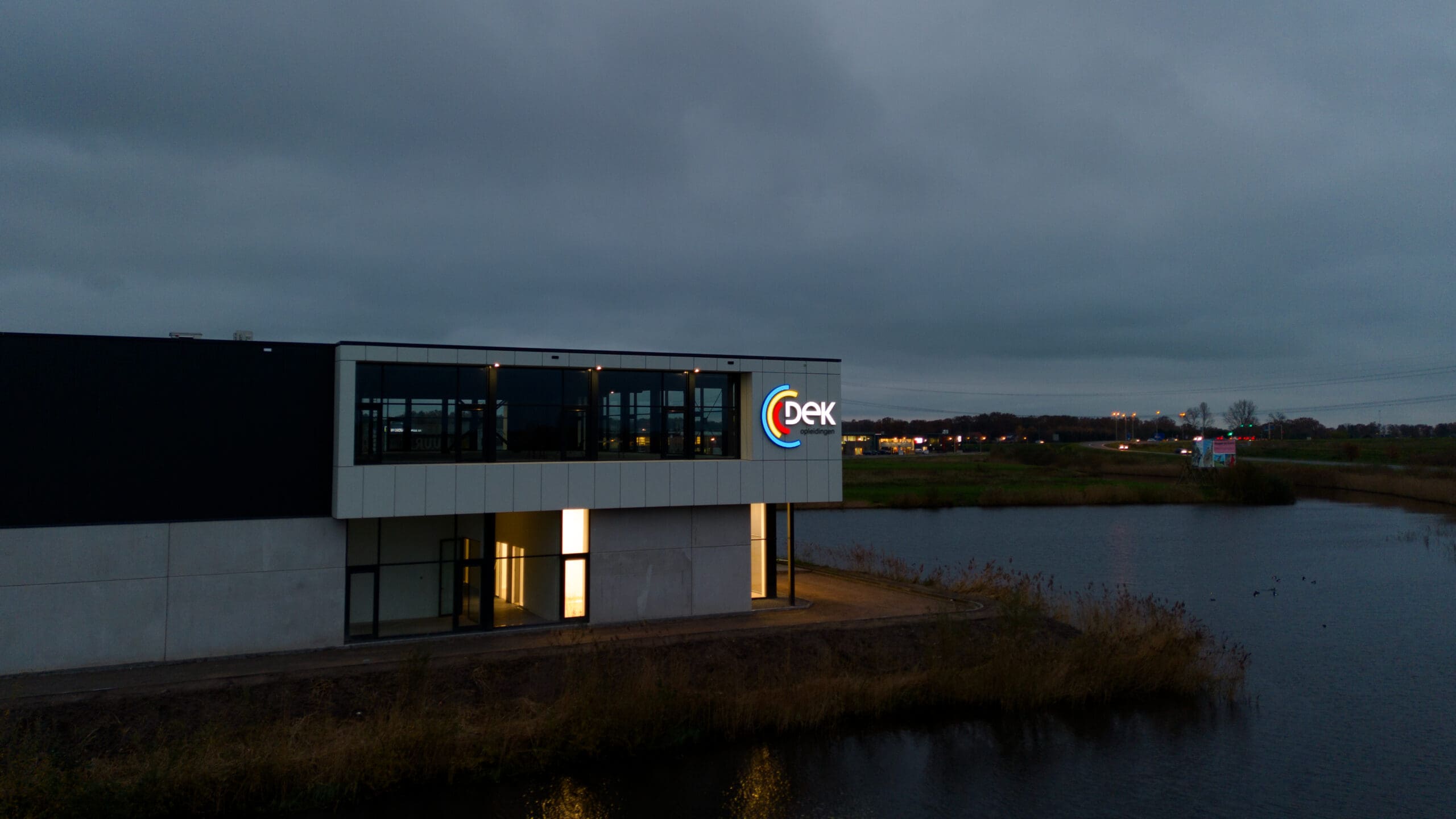 Verlichte gevelreclame DEK opleidingen bij nieuw pand in Halsteren langs de A4