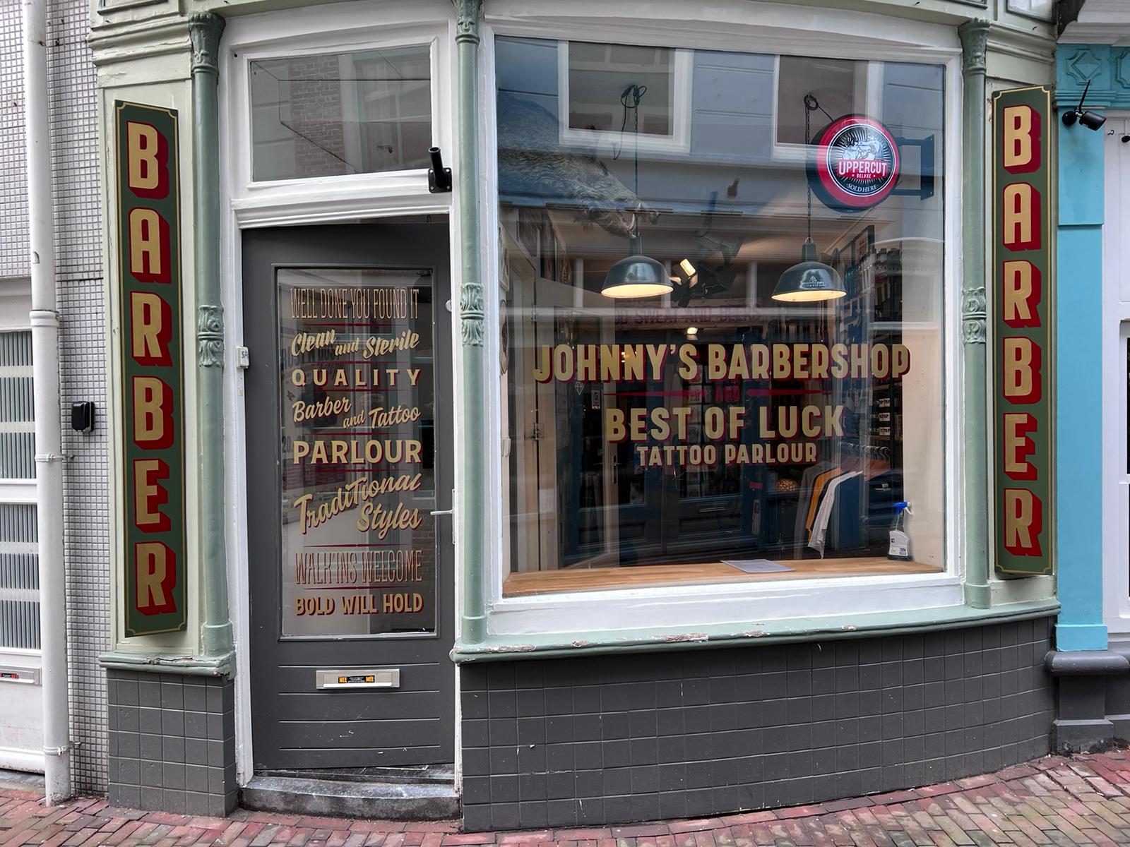 Raambelettering deur en raam van Johnny's barbershop
