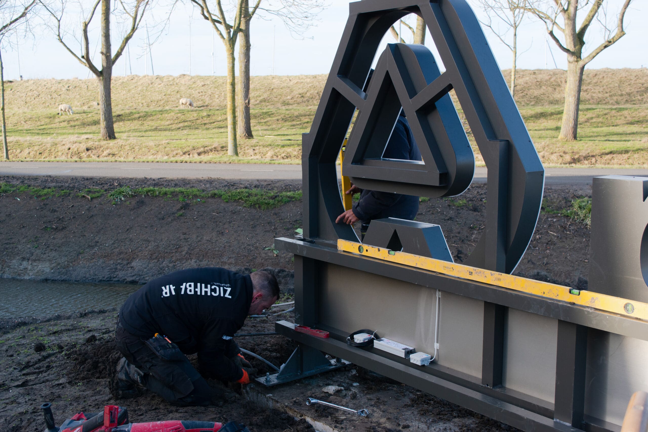 Close up van monteurs die bezig zijn met de montage van een reclame uiting bij nemag